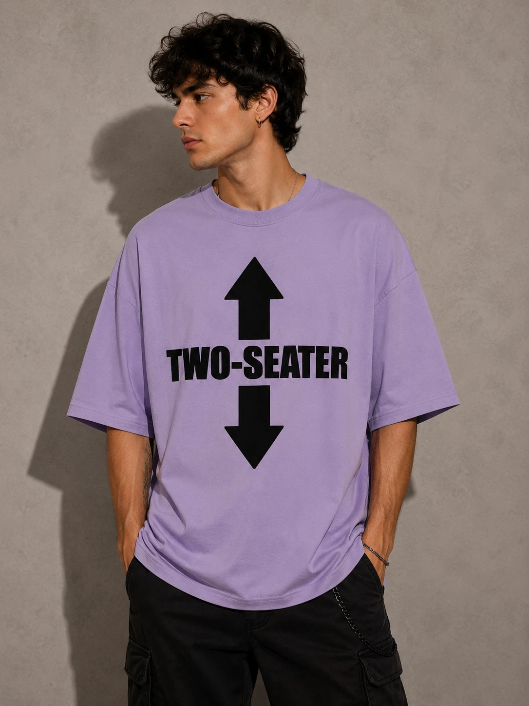 Model in a lilac oversized tee reading two-seater between two arrows